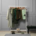 Kledingrek met stijlvolle dameskleding, schoenen en tas, gepresenteerd in een moderne modewinkel.