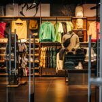 Donker interieur van een sportwinkel met kleding, schoenen en accessoires, sfeervol gepresenteerd in een moderne retailomgeving.